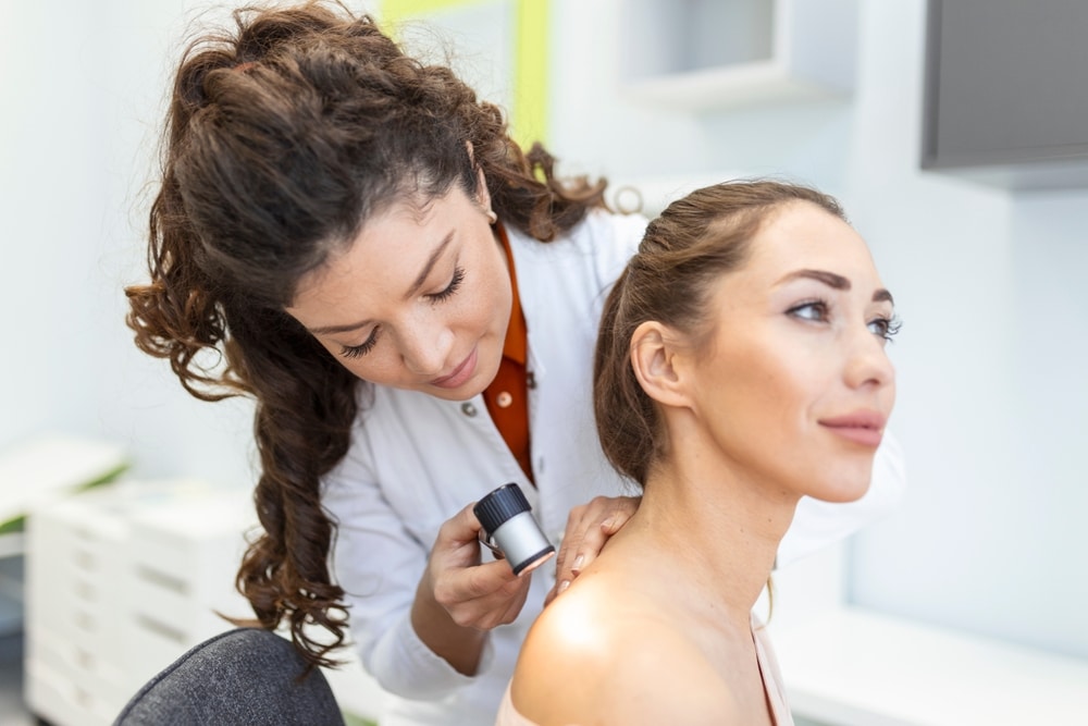Dermatologist using dermatoscope to examine patient’s skin for signs of disease or skin cancer.