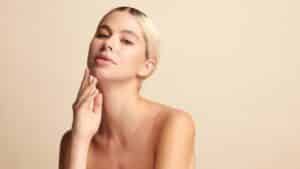 Beautiful young woman with clean, fresh skin posing on beige background, concept of face care, facial treatment, and spa beauty.