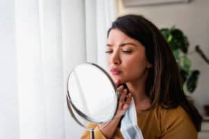 Woman looking at her skin up close in the mirror