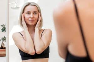A woman looking in the mirror after a mini facelift in Austin, TX