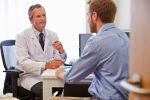 Male patient discussing Mohs surgery recovery with dermatologist.
